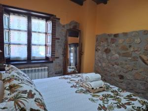 een slaapkamer met een bed met een stenen muur bij casa PUMARADA in Sardeda