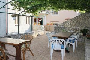 een buitenterras met houten tafels en stoelen bij Apartment Njivice 5458f in Njivice