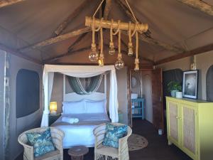 a bedroom with a canopy bed and two chairs at Trekosglamping luxury tents 