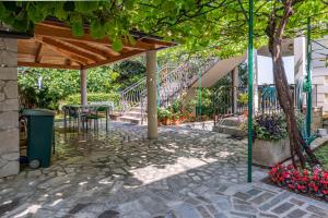 a patio with a table and a staircase with flowers at Apartments by the sea Lovran, Opatija - 7837 in Lovran