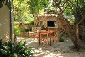 a table and chairs in a garden with a stone oven at Apartments with parking space Jelsa, Hvar - 8750 in Jelsa