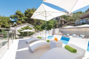 a patio with white chairs and an umbrella and a pool at Seaside apartments with a swimming pool Prigradica, Korcula - 9290 in Prigradica