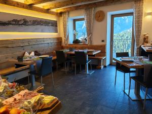 a restaurant with tables and chairs and a large window at Al Sole B&B Valcomelico in Santo Stefano di Cadore