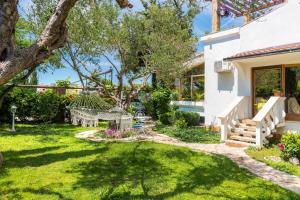 un jardin avec un banc et un arbre dans l'établissement Luxury villa with a swimming pool Rogoznica - 13374, à Rogoznica