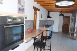 a kitchen with a counter and two stools in it at Gîte du Lieu Piquot in Gréville-Hague
