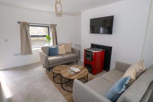 ein Wohnzimmer mit zwei Sofas und einem Fernseher in der Unterkunft Rose Cottage in Killala