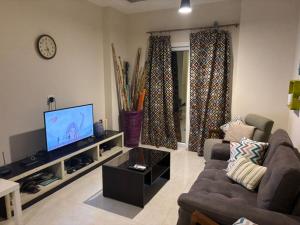 a living room with a couch and a flat screen tv at Quiet HOME in Hurghada