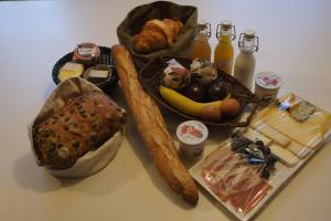a table with bread and other foods and drinks at Au Petit Bercail - 2 Chambres d'hôtes pour 2 personnes in Chiny