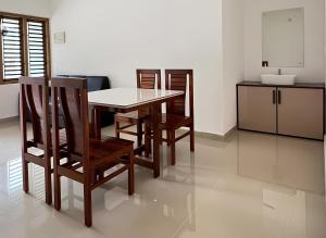 een keuken met een tafel en stoelen in een kamer bij Easy Nest Residency in Kannur