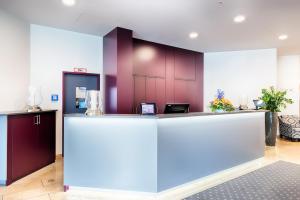 a lobby with a reception counter with purple walls at ACHAT Hotel Neustadt an der Weinstraße in Neustadt an der Weinstraße