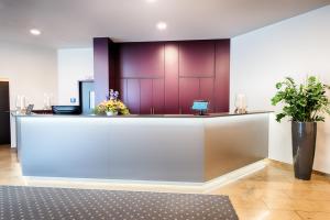 a lobby with a reception desk with purple walls at ACHAT Hotel Neustadt an der Weinstraße in Neustadt an der Weinstraße