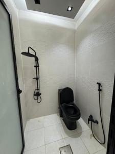 a bathroom with a black toilet and a shower at سويت بني معن in Al Hofuf