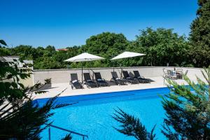 une piscine avec chaises longues et parasols dans l'établissement Family friendly house with a swimming pool Krnica, Marcana - 24375, à Krnica