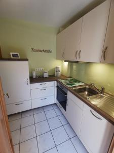 a kitchen with white cabinets and a sink at Ferienwohnung Am Heimathof in Dorsten
