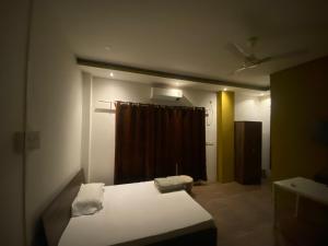 a bedroom with a bed and a brown curtain at Brookside Inn in Dibrugarh