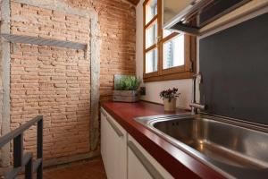 a kitchen with a sink and a brick wall at Appartamento Piazzetta 5 by ElbaSummer in Portoferraio +12 photos