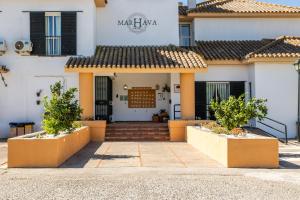 Un edificio blanco con una entrada acogedora y árboles al frente. en Hotel Marhava, en Conil de la Frontera