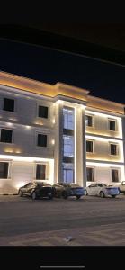 a large white building with cars parked in front of it at شقق المصيف الفندقيه in Hafr Al Baten