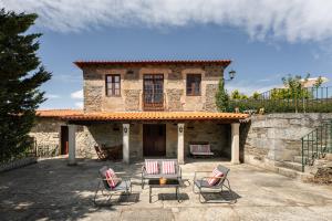 a stone house with four chairs in front of it at Casa de Sao Miguel Douro in Armamar