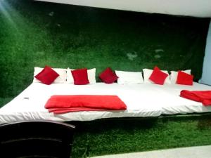 Una cama grande con almohadas rojas y blancas. en Hotel #Shreeeee Krishnaaaaa# Near रेलवे स्टेशन, en Bhubaneshwar