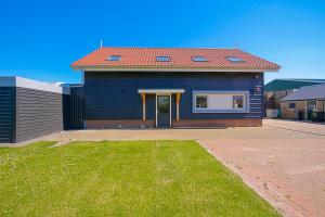 a blue house with a red roof and a yard at New! Guesthouse Eindeloos in 't Zand +19 photos