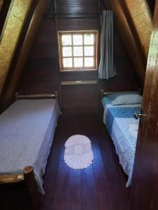 a attic room with two beds and a window at Recanto Mauá - Chalé Amarílis in Resende