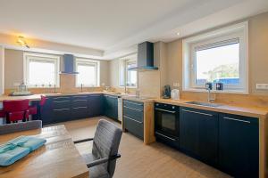 a large kitchen with blue cabinets and a table at New! Guesthouse Eindeloos in 't Zand