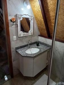 a bathroom with a sink and a mirror at Recanto Mauá - Chalé Amarílis in Resende +33 photos