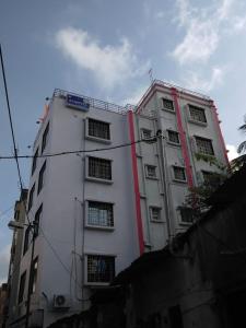 un edificio blanco alto con un letrero azul. en Hotel AI Near Shalimar railway station, en Howrah
