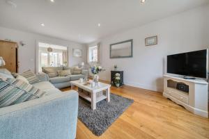 un salon avec un canapé et une télévision dans l'établissement Curlew Cottage, à Brancaster