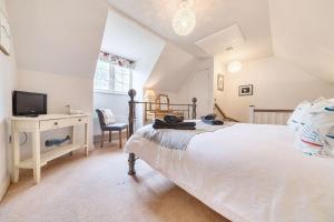 une chambre avec un lit, un bureau et une télévision dans l'établissement Curlew Cottage, à Brancaster