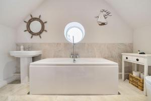 une salle de bain avec une baignoire blanche et un lavabo dans l'établissement Curlew Cottage, à Brancaster 21 autres photos