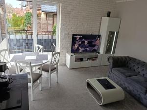 a living room with a couch and a tv and a table at Apartament Brzeg in Brzeg