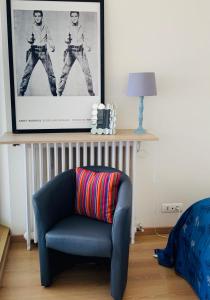 ein Wohnzimmer mit einem blauen Stuhl und einem Bild in der Unterkunft Chambre & terrasse face océan in Royan