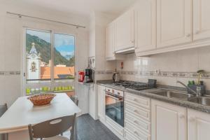 a kitchen with white cabinets and a sink and a window at Ribeira brava - duplex sea view in Ribeira Brava