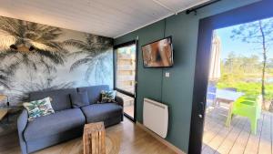 a living room with a blue couch and a large window at LE COTTAGE VUE LAC-2 vélos-Village Vacances Nature de 70ha! avec piscines et animations in Léon