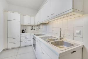 a white kitchen with a sink and white cabinets at Moderne Traumwohnung mit Traumgarten in Mayen