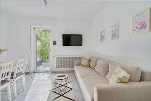 a white living room with a couch and a tv at Moderne Traumwohnung mit Traumgarten in Mayen