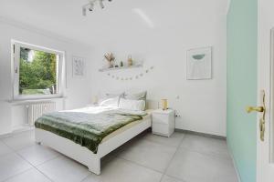 a white bedroom with a bed and a window at Moderne Traumwohnung mit Traumgarten in Mayen