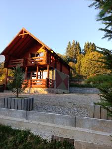 eine große Holzhütte mit Zaun und Bäumen in der Unterkunft Котедж Арніка in Worochta