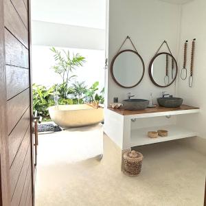 une salle de bain avec deux lavabos et une baignoire dans l'établissement Villa JAYA Nyanyi, à Munggu