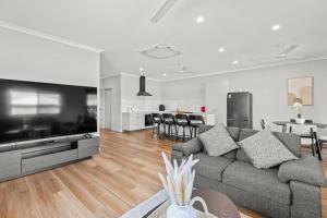 a living room with a gray couch and a kitchen at Broome Villa Oasis in Broome