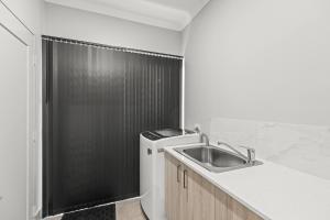 a kitchen with a sink and a black shower at Broome Villa Oasis in Broome