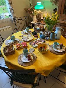 a table with a yellow table cloth with food on it at Les Ondines in Estréelles