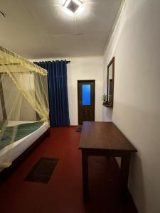 Cette chambre comprend un lit et une table en bois. dans l'établissement Dimuthu Cottage Hiriketiya, à Dikwella