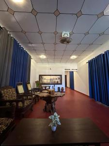 un salon avec des rideaux bleus et une table et des chaises dans l'établissement Dimuthu Cottage Hiriketiya, à Dikwella