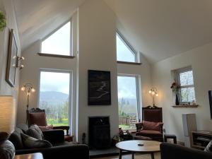 a living room with three windows and a fireplace at Oiseval in Fort Augustus