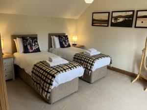a bedroom with two beds and two tables and lamps at Oiseval in Fort Augustus