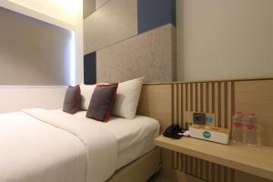 een hotelkamer met een bed en een klok op een toonbank bij IXO Hotel Semarang in Stasiun Tawang +9 foto's