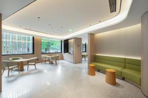 a lobby with a green couch and tables and chairs at JI Hotel Beijing Fangzhuang Puhuangyu Subway Station in Beijing
